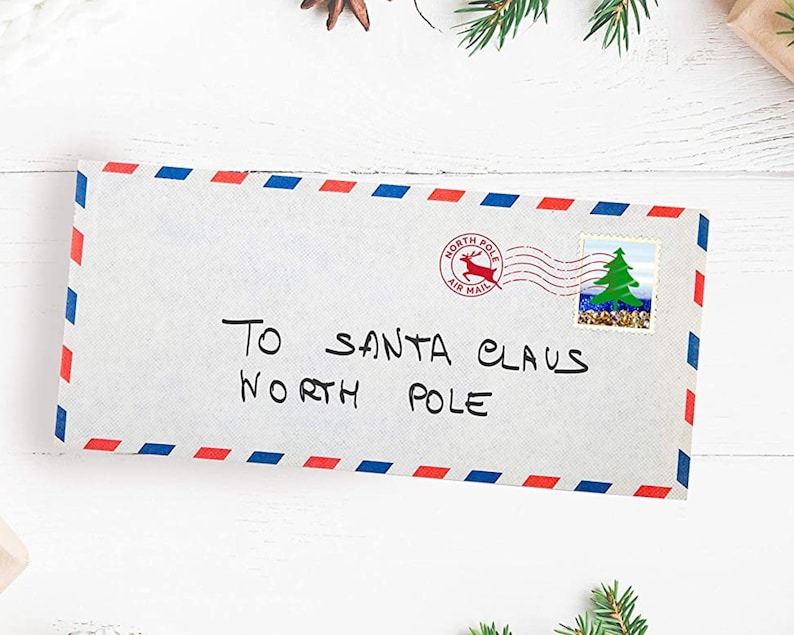 May include: A white envelope with red and blue stripes along the edges. The envelope is addressed to "To Santa Claus North Pole" with a red and blue "North Pole Air Mail" stamp with a reindeer and a green Christmas tree stamp.