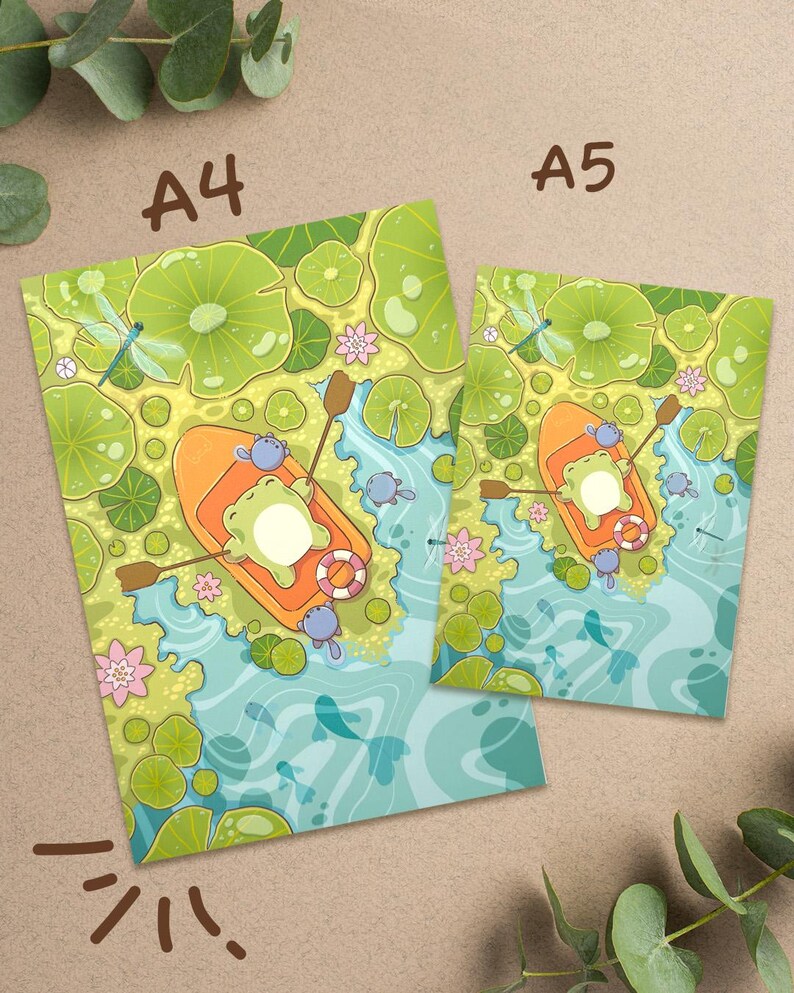 May include: Two art prints, A4 and A5 sizes, featuring a whimsical illustration of a frog in an orange boat on a pond. The scene includes lily pads, dragonflies, and fish, with the text "A4" and "A5" on the prints.