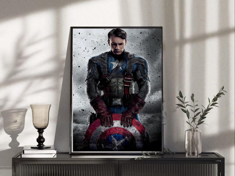 May include: Framed print featuring Captain America, holding his shield. The artwork depicts the superhero in his iconic costume, with a star on his chest and a red, white, and blue shield. The image has a gritty, textured background.