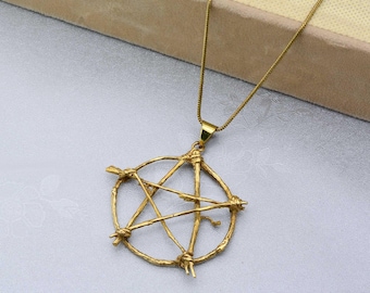 May include: A gold necklace with a pentagram pendant. The pendant is made of twisted metal that resembles branches.