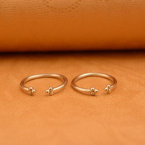 May include: Two gold rings with a cluster of three small balls on each side.