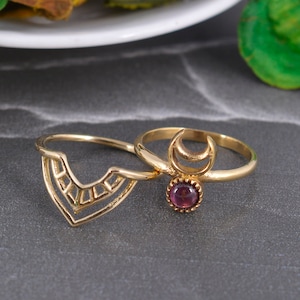 Può includere: Due anelli d'oro con un design geometrico. Un anello presenta una mezzaluna e una piccola pietra preziosa viola.