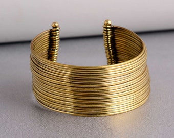 May include: A gold-toned bangle bracelet made of multiple thin, stacked bands.