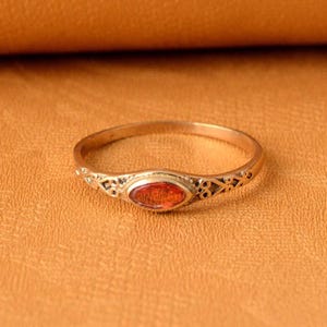 May include: A gold ring with an oval-shaped red gemstone set in a delicate filigree design.
