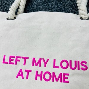 May include: White canvas tote bag with rope handles and pink embroidered text that reads "LEFT MY LOUIS AT HOME".