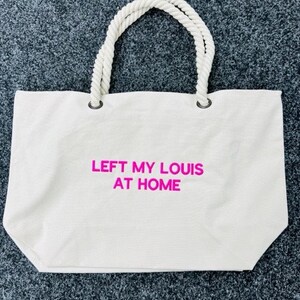 May include: White canvas tote bag with rope handles and the text "LEFT MY LOUIS AT HOME" in pink.