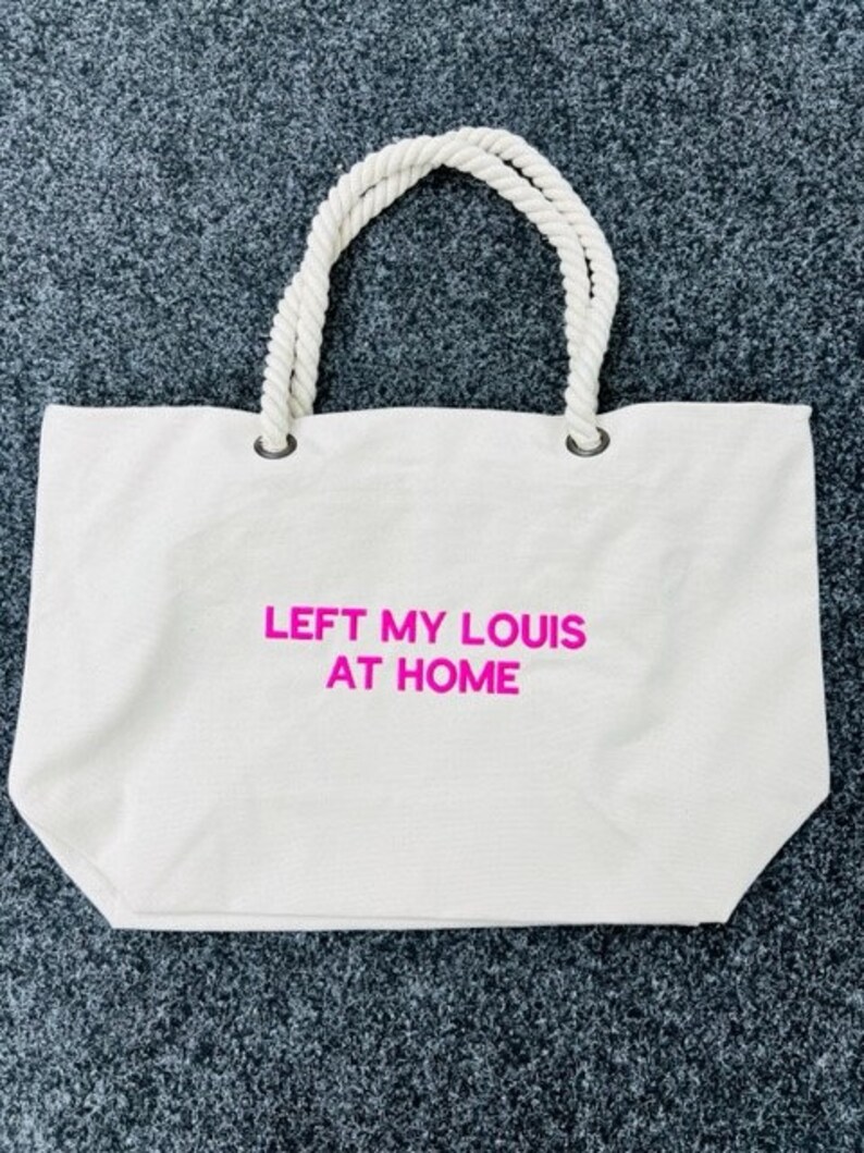 May include: White canvas tote bag with rope handles and the text "LEFT MY LOUIS AT HOME" in pink.