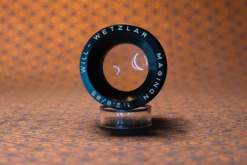 Puede incluir: Una taza de cer&aacute;mica blanca con un asa negra y el texto "But First, Coffee" en un estilo manuscrito. La taza est&aacute; sobre una superficie blanca. La taza mide 10 cm de alto.