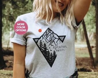 May include: A grey t-shirt with a black and white graphic of a mountain range with trees and the text "Adventure Awaits".