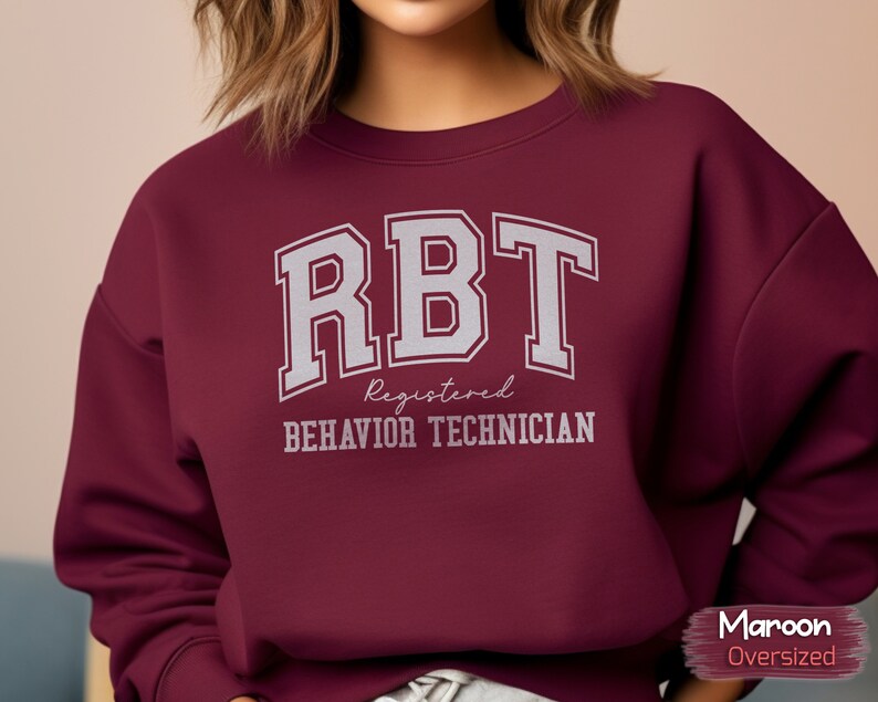 May include: Maroon oversized sweatshirt with the text "RBT Registered Behavior Technician" in white.