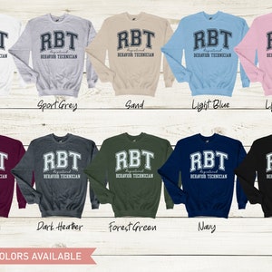 May include: A variety of colors of sweatshirts with the text "RBT Registered Behavior Technician" printed on the front. The text is in a collegiate font with a white outline.