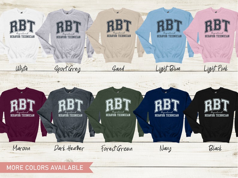 May include: A variety of colors of sweatshirts with the text "RBT Registered Behavior Technician" printed on the front. The text is in a collegiate font with a white outline.