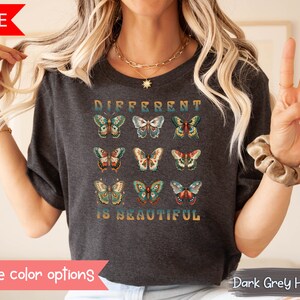 May include: Dark grey heather t-shirt with a graphic of colorful butterflies and the text "Different is Beautiful".