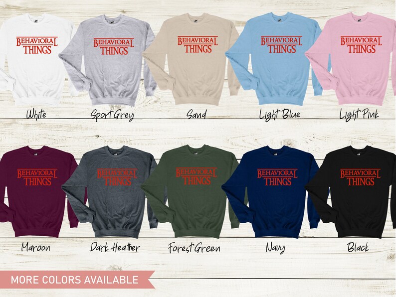 May include: A variety of colors of sweatshirts with the text "BEHAVIORAL THINGS" printed in red on the front. The text is in a bold, sans-serif font and is enclosed in a red rectangle. The sweatshirts are available in white, sport grey, sand, light blue, light pink, maroon, dark heather, forest green, navy, and black.
