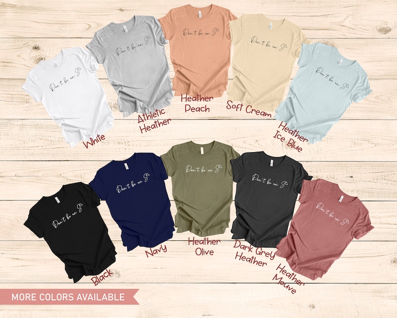 May include: A range of t-shirts in various colours, including white, black, navy, heather peach, heather olive, heather grey, heather ice blue, heather mauve, and athletic heather. Each shirt features the text "Don't be a  " in a white script font.
