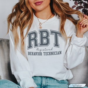 May include: White sweatshirt with the text "RBT Registered Behavior Technician" in a gray collegiate font.