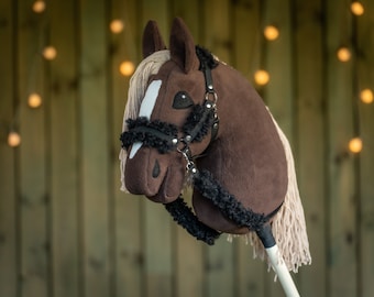 May include: A brown and white horse head with a black and white bridle. The horse head is made of fabric and is a toy.