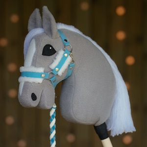 May include: A gray and white rocking horse head with a blue and white bridle. The horse has a white mane and tail.