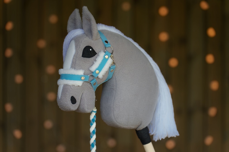 May include: A gray and white rocking horse head with a blue and white bridle. The horse has a white mane and tail.