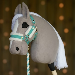 May include: A gray and white stuffed horse head with a turquoise and gold bridle. The horse has a white mane and tail.