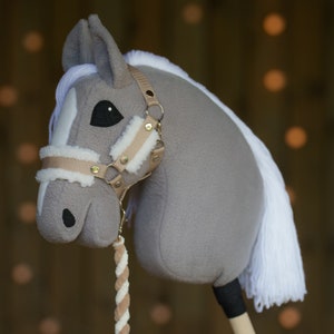 May include: A gray and white plush rocking horse with a brown leather halter and reins. The horse has a white mane and tail.