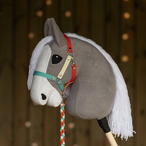 May include: A gray and white plush rocking horse with a red, yellow, and blue bridle. The horse has a white mane and tail.