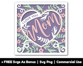 May include: A purple heart-shaped design with a white outline and the word "Mom" in pink script inside. The heart is surrounded by a white floral pattern on a purple background. The text "I Love You" is written on a white banner inside the heart.