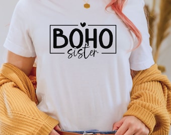 May include: White t-shirt with black text that reads "BOHO sister" in a box with a small heart above the text.