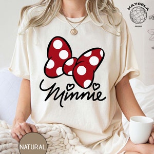May include: A white t-shirt with a red and white polka dot bow and the word "Minnie" in black script.
