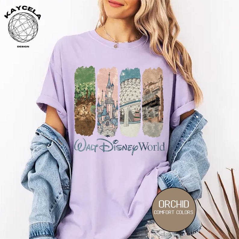 Op de afbeelding: Een lichtpaars t-shirt met een afbeelding van Walt Disney World-bezienswaardigheden. Het ontwerp bevat afbeeldingen van een kasteel, een boom en andere parkkenmerken. De tekst "Walt Disney World" staat onder de afbeeldingen. Het shirt heeft ook de tekst "Orchid Comfort Colors".