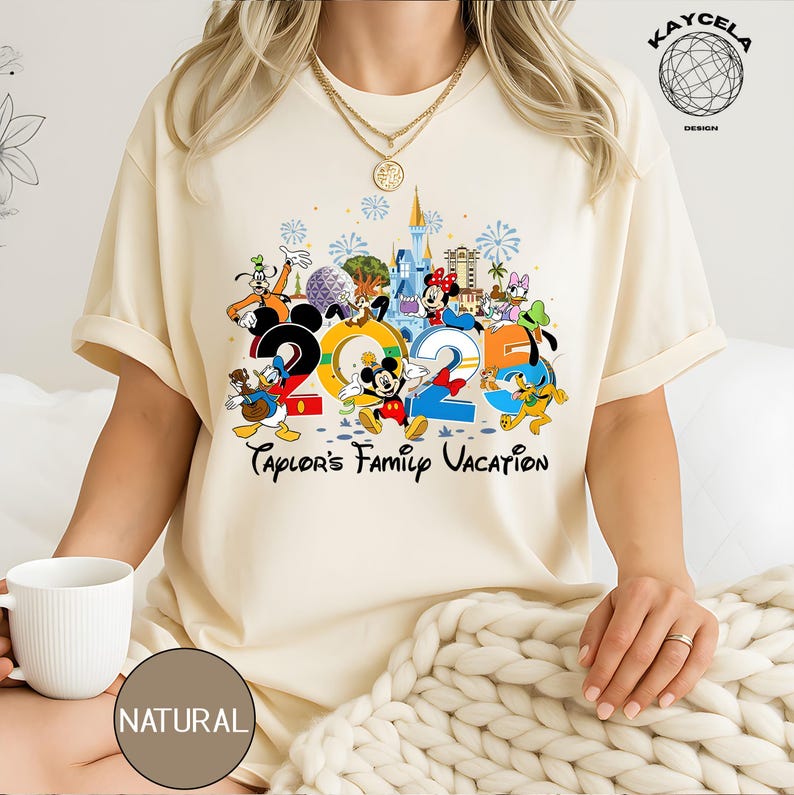 Puede incluir: Camiseta color crema con un gr&aacute;fico colorido de personajes de Disney y el texto "2025 Taylor's Family Vacation". El dise&ntilde;o incluye Mickey Mouse, Minnie Mouse, Donald Duck y Goofy, con un castillo y fuegos artificiales.
