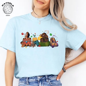 K&ouml;nnte beinhalten: Hellblaues T-Shirt mit einem Aufdruck des Wortes "MAMA", das aus Figuren des Animationsfilms Vaiana besteht. Die Figuren sind Vaiana, Maui, Pua das Schwein, Hei Hei der Hahn und der Halbgott Maui.