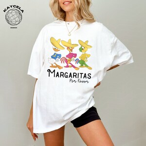 May include: White t-shirt with a graphic of three cartoon characters wearing sombreros and the text "Margaritas Por Favor".
