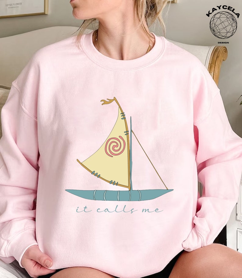 May include: Pink sweatshirt with a cartoon image of a sailboat and the text "it calls me".
