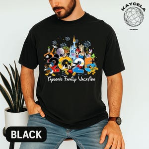 Puede incluir: Camiseta negra con un dise&ntilde;o gr&aacute;fico colorido con los n&uacute;meros "2023" y personajes de Disney. El dise&ntilde;o incluye a Mickey Mouse, el Pato Donald y Minnie Mouse, con el texto "Taylor's Family Vacation". La palabra "BLACK" est&aacute; impresa abajo.