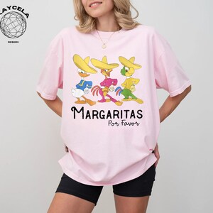 May include: Pink t-shirt with a graphic of three cartoon characters wearing sombreros and the text "Margaritas Por Favor".
