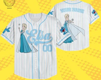 May include: White baseball jersey with light blue pinstripes, featuring the name "Elsa" and the number "00" in light blue. The jersey has illustrations of Elsa and a cartoon character. The back of the jersey says "YOUR NAME".