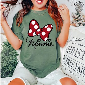 May include: A green t-shirt with a red and white polka dot bow and the word "Minnie" in black script.