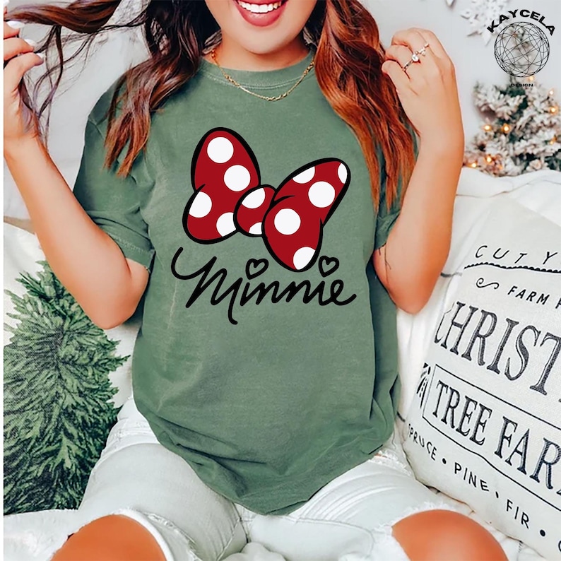 May include: A green t-shirt with a red and white polka dot bow and the word "Minnie" in black script.