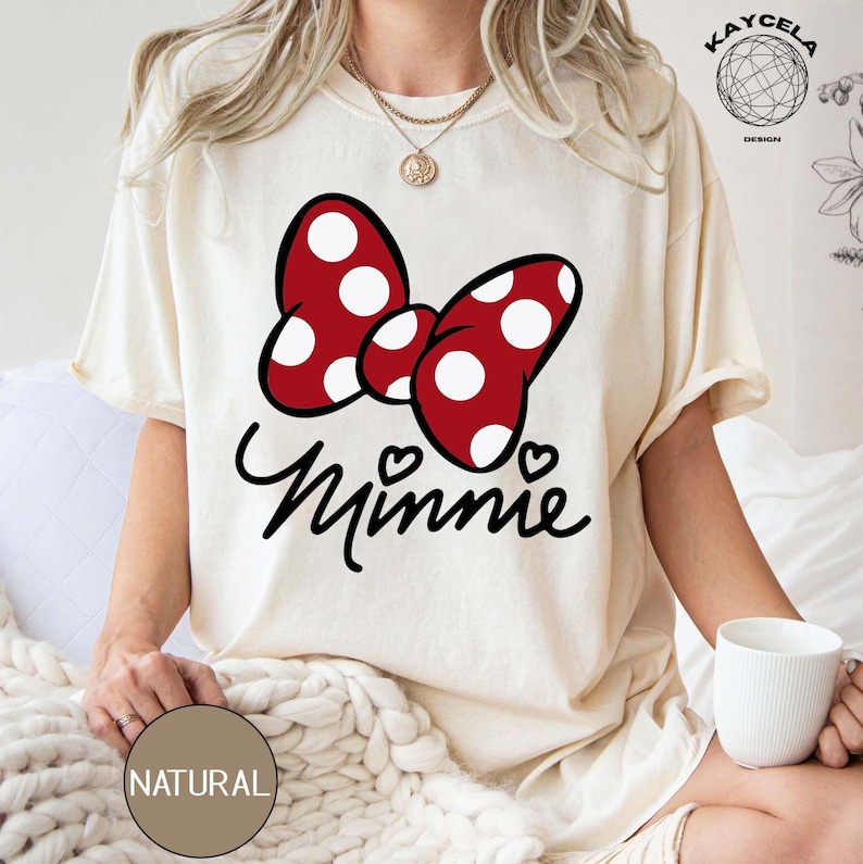 May include: A white t-shirt with a red and white polka dot bow and the word "Minnie" in black script.