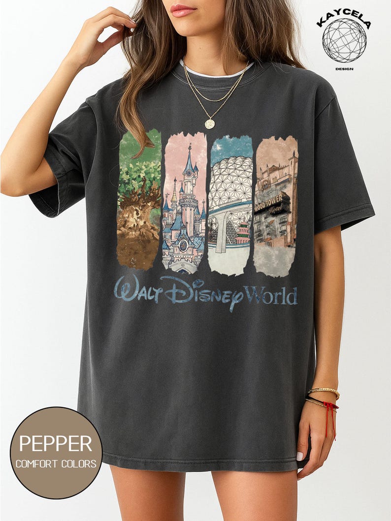 Op de afbeelding: Donkergrijs t-shirt met een kleurrijke afbeelding van Walt Disney World-bezienswaardigheden. Het ontwerp bevat afbeeldingen van een boom, een kasteel, een geodetische bol en een hotel, met "Walt Disney World" in blauw schrift. Het shirt heeft een Pepper Comfort Colors label.