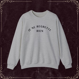 May include: A gray sweatshirt with the French phrase "Je ne regrette rien" printed in black on the front.