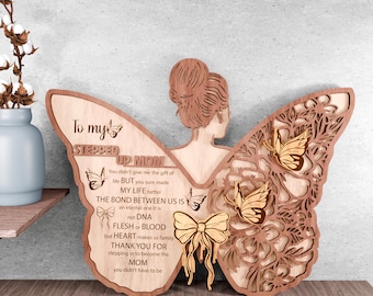 May include: Wooden cutout of a woman with butterfly wings, with a message that reads "To my Stepped Up Mom. You didn't give me the gift of life BUT you sure made MY LIFE better. THE BOND BETWEEN US IS an eternal one it is not DNA. FLESH or BLOOD but HEART makes us family. THANK YOU FOR stepping in to become the MOM you didn't have to be."