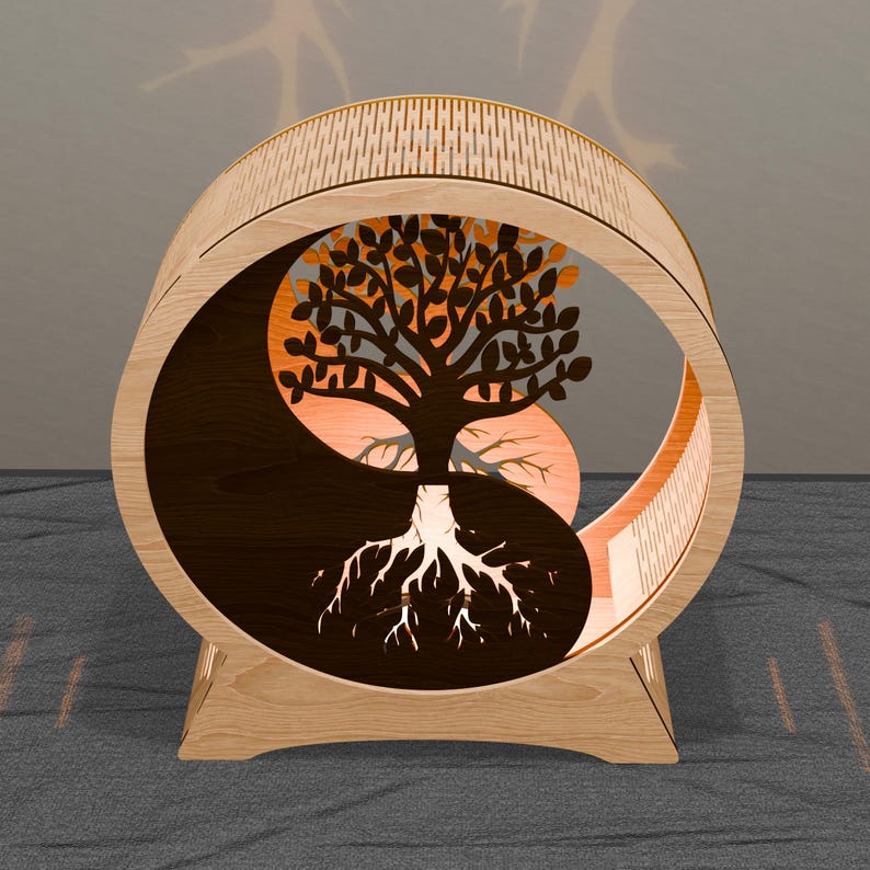 May include: A wooden decorative piece featuring a tree design within a Yin and Yang symbol. The tree has detailed leaves and roots, with a light-colored wood frame and a patterned top. The design is illuminated with warm orange light.