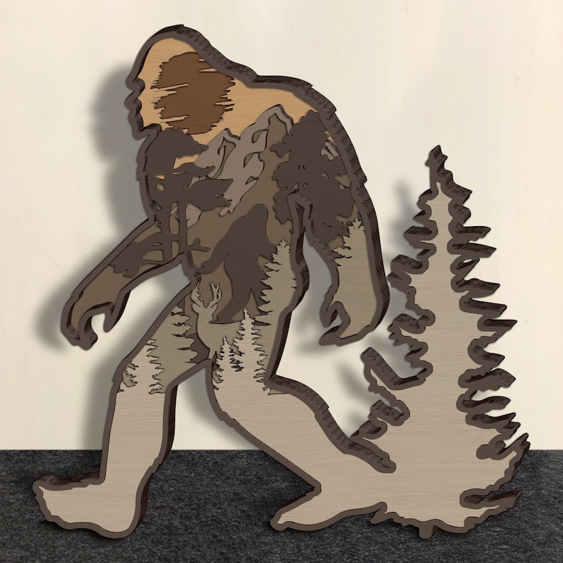 May include: A brown silhouette of Bigfoot walking through a forest with a large pine tree in the background. The silhouette is made of wood and has a layered effect, showing the different layers of the forest.