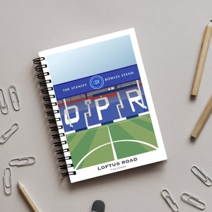 Könnte beinhalten: Ein blaues und weißes Spiralnotizbuch mit einer Grafik von Loftus Road, der Heimat des Queens Park Rangers, einem Fußballverein in London, England. Das Notizbuch trägt den Text "Loftus Road" und "The Hoops" auf der Vorderseite.