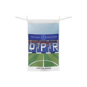 Könnte beinhalten: Ein weißes Geschirrtuch mit einer blauen und roten Illustration von Loftus Road, dem Heimstadion des Queens Park Rangers Football Club. Der Text "Loftus Road" und "The Hoops" ist unter der Illustration gedruckt.