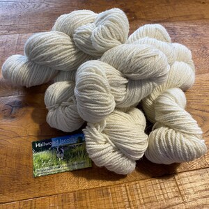 May include: Several off-white yarn skeins. The yarn is thick and appears to be made of natural fibres. A business card with the text "Hallwood Jacobs" and a pastoral scene is visible.