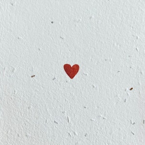 K&ouml;nnte beinhalten: Ein einzelnes rotes Herz auf wei&szlig;em Hintergrund mit gesprenkelter Textur.