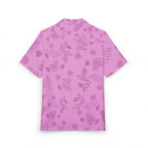 May include: A short-sleeved button-down shirt in a light pink hue, adorned with a repeating pattern of stylized leaves and botanical elements in a slightly darker shade of pink. The shirt has a classic collar and a relaxed fit, suitable for casual wear.